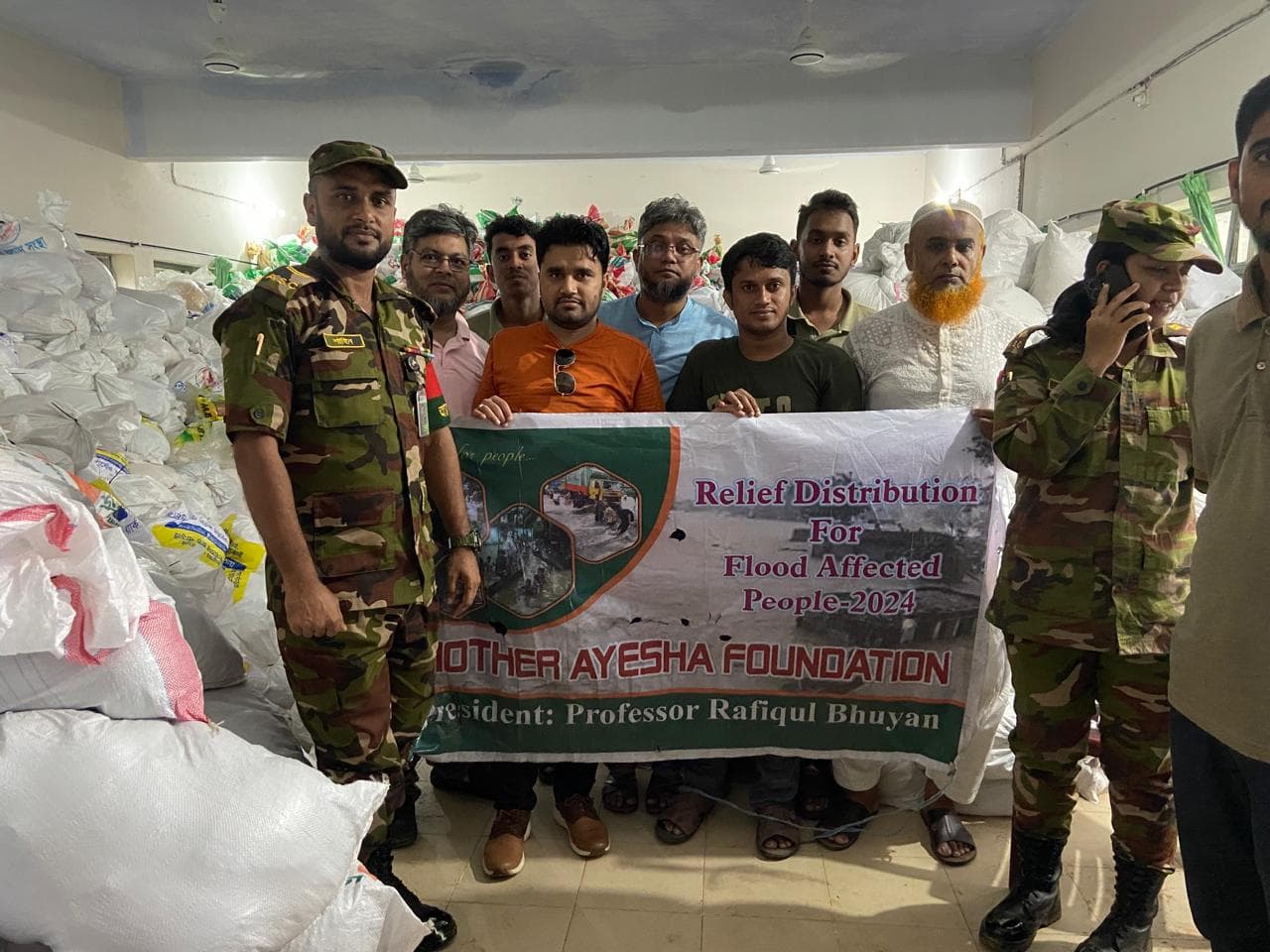 Volunteers of Mother Ayesha Foundation and members of the Bangladesh Army stand together with relief supplies prepared for flood-affected communities in Burichang, Cumilla, Bangladesh.