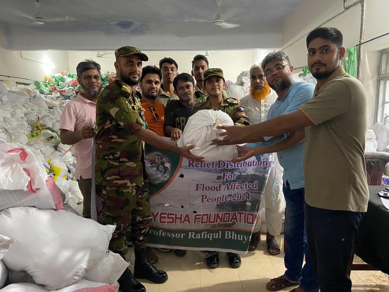 Representatives of Mother Ayesha Foundation hand over dry food relief packages to Bangladesh Army personnel for distribution among flood-affected families in Burichang, Cumilla, Bangladesh.