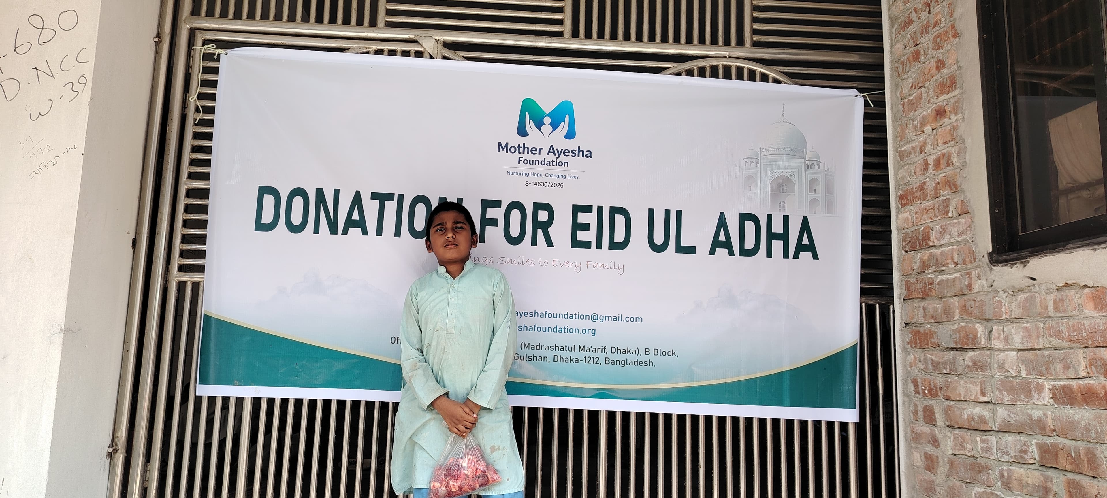 A child receiving Qurbani meat during the Mother Ayesha Foundation Eid-ul-Adha distribution campaign.
