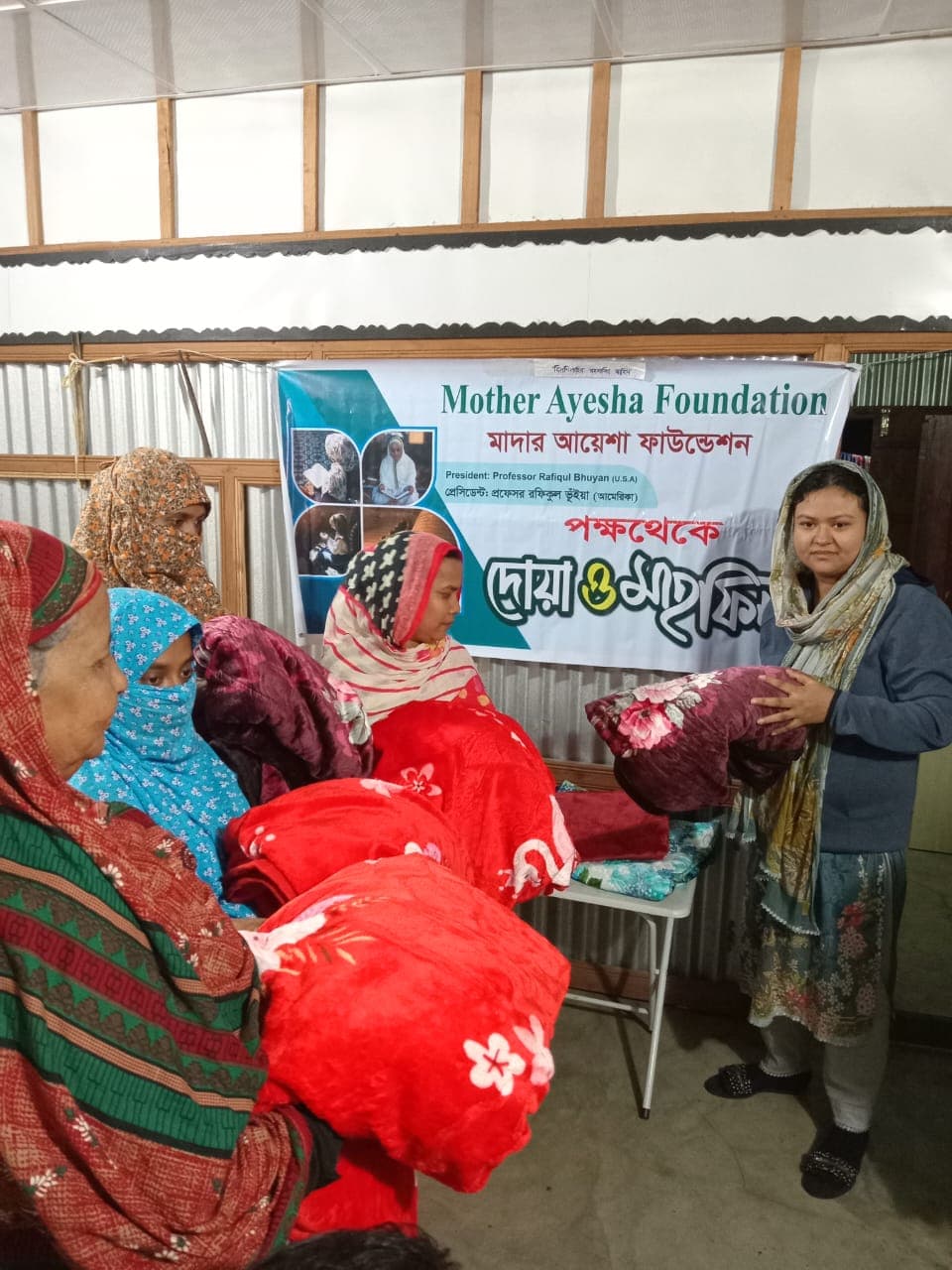 Giving away blankets and warm clothes to women from the village at Mother Ayesha Foundation's winter relief distribution event