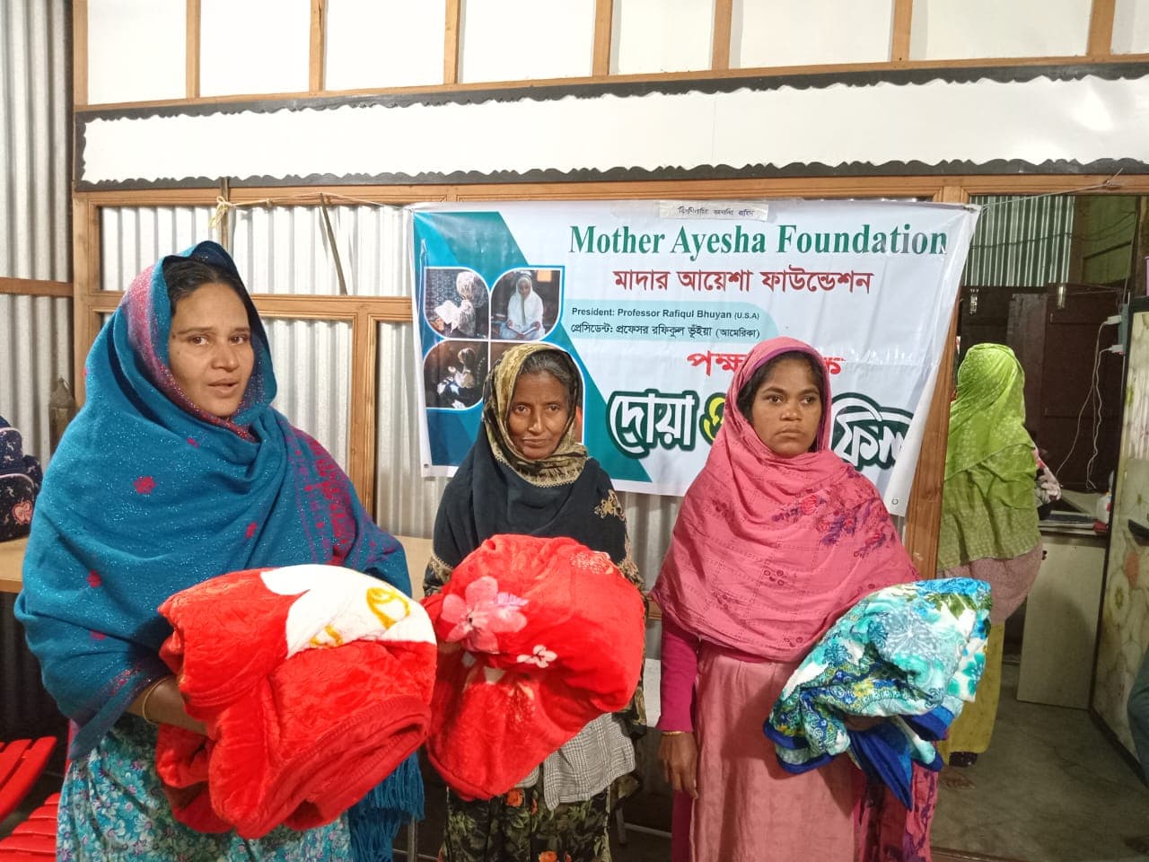 Giving away blankets to peoples from the village at Mother Ayesha Foundation's winter relief distribution event