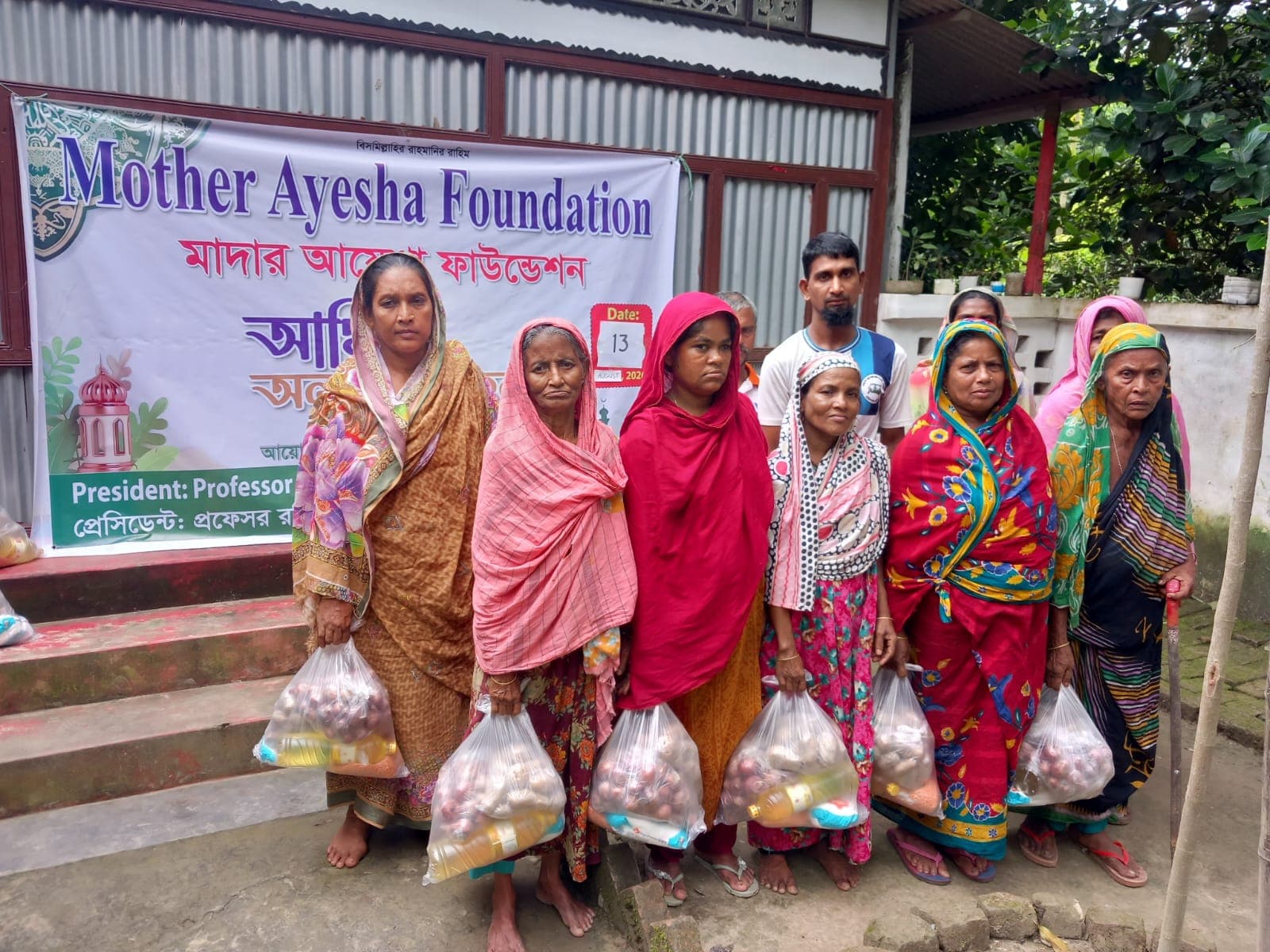 Families holding food assistance packages provided by Mother Ayesha Foundation