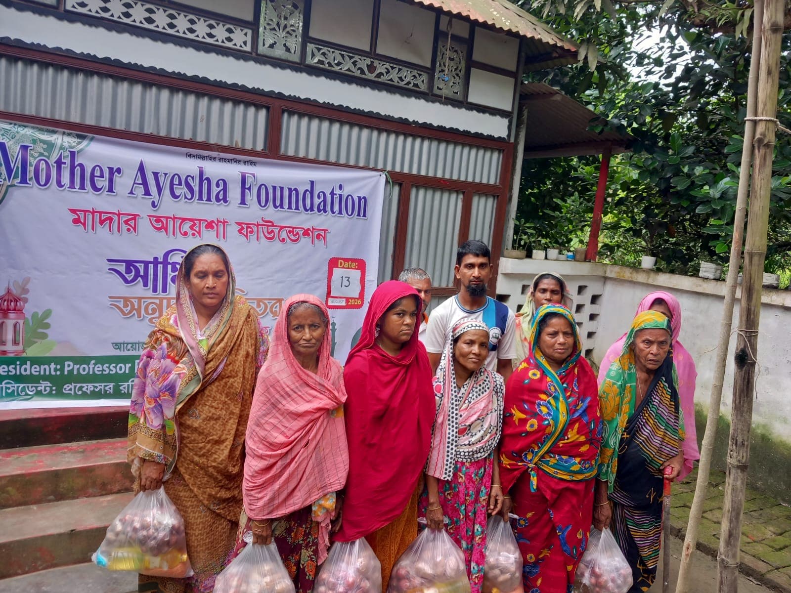 Community members standing with food assistance packages distributed by Mother Ayesha Foundation
